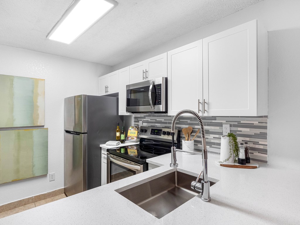 A kitchen with a stainless steel refrigerator and a microwave above the stove.